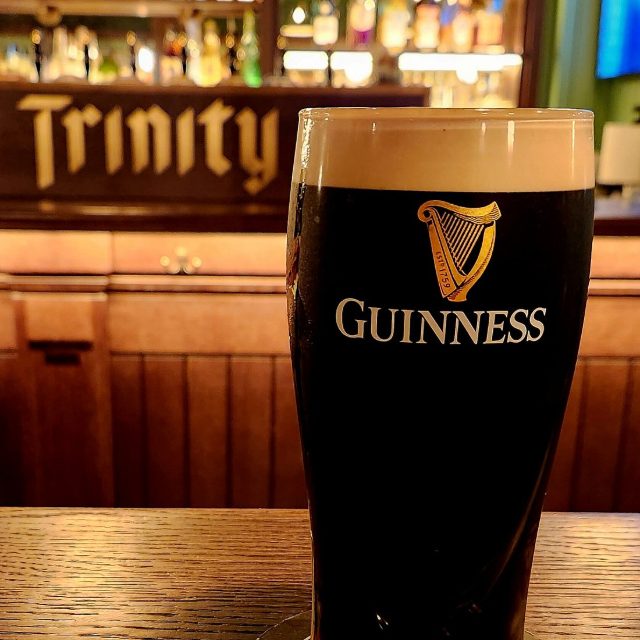 A fresh pint of Guinness on the bar in front of the Trinity sign